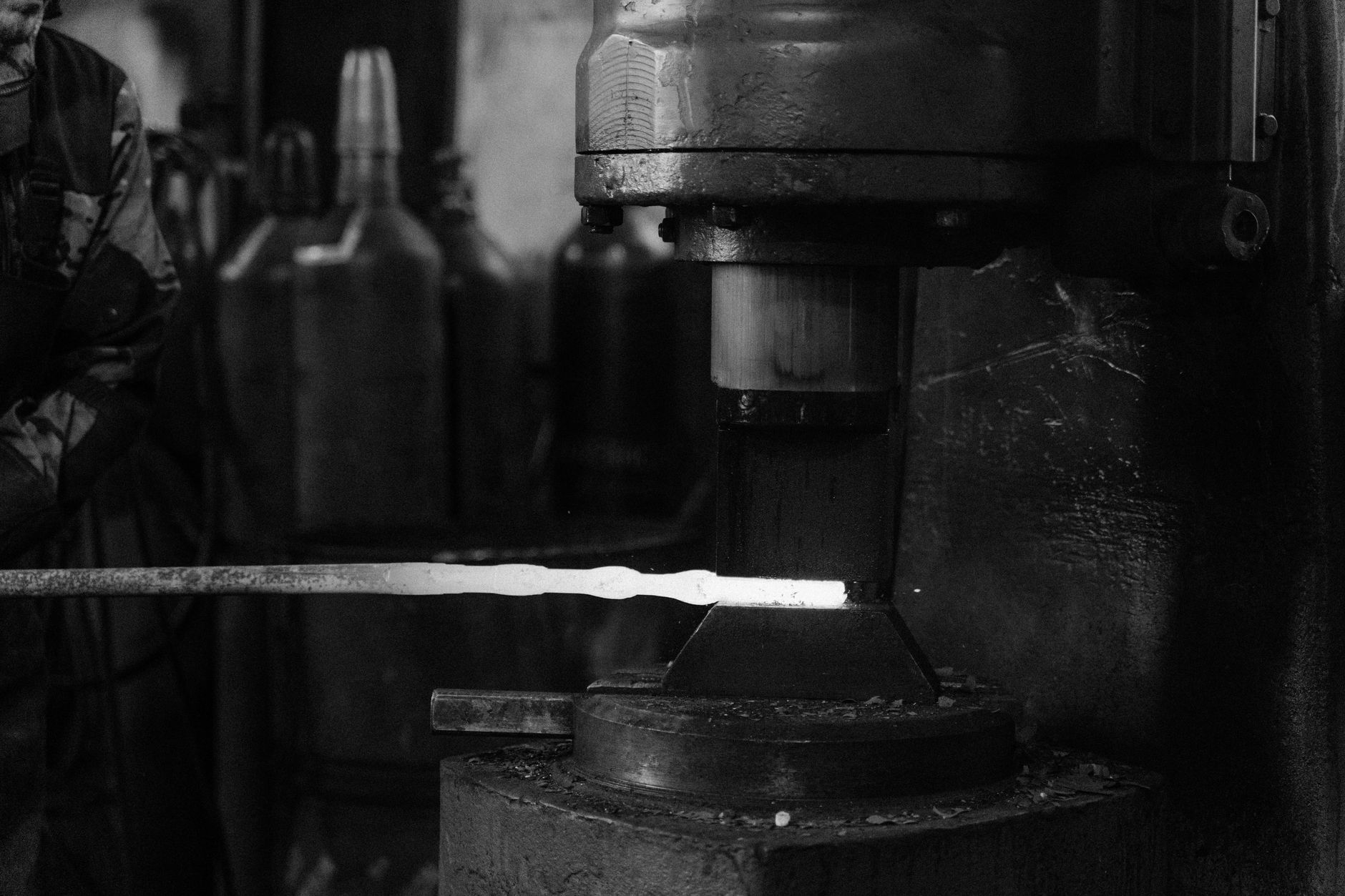 Kuvituskuva: takomon puristinkone ja metallitanko